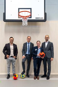 vier Personen stehen in der neuen Turnhalle der Christophorusschule Erfurt mit bunten Bällen und freuen sich anlässlich der Eröffnung